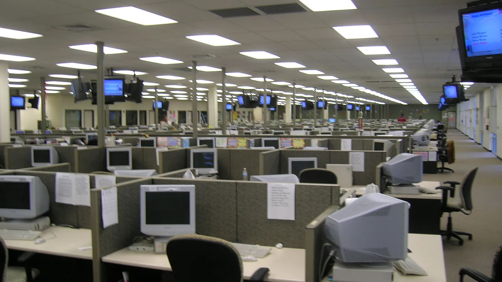 Rows of empty desks and computers on a large customer support floor