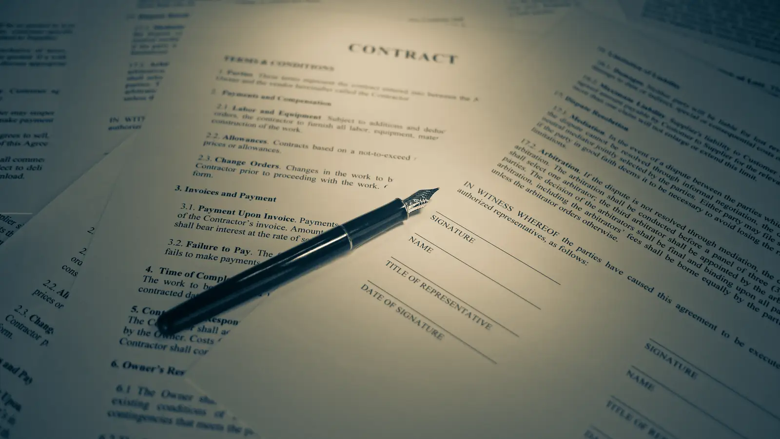A printed contract and a pen lit by a warm desk lamp