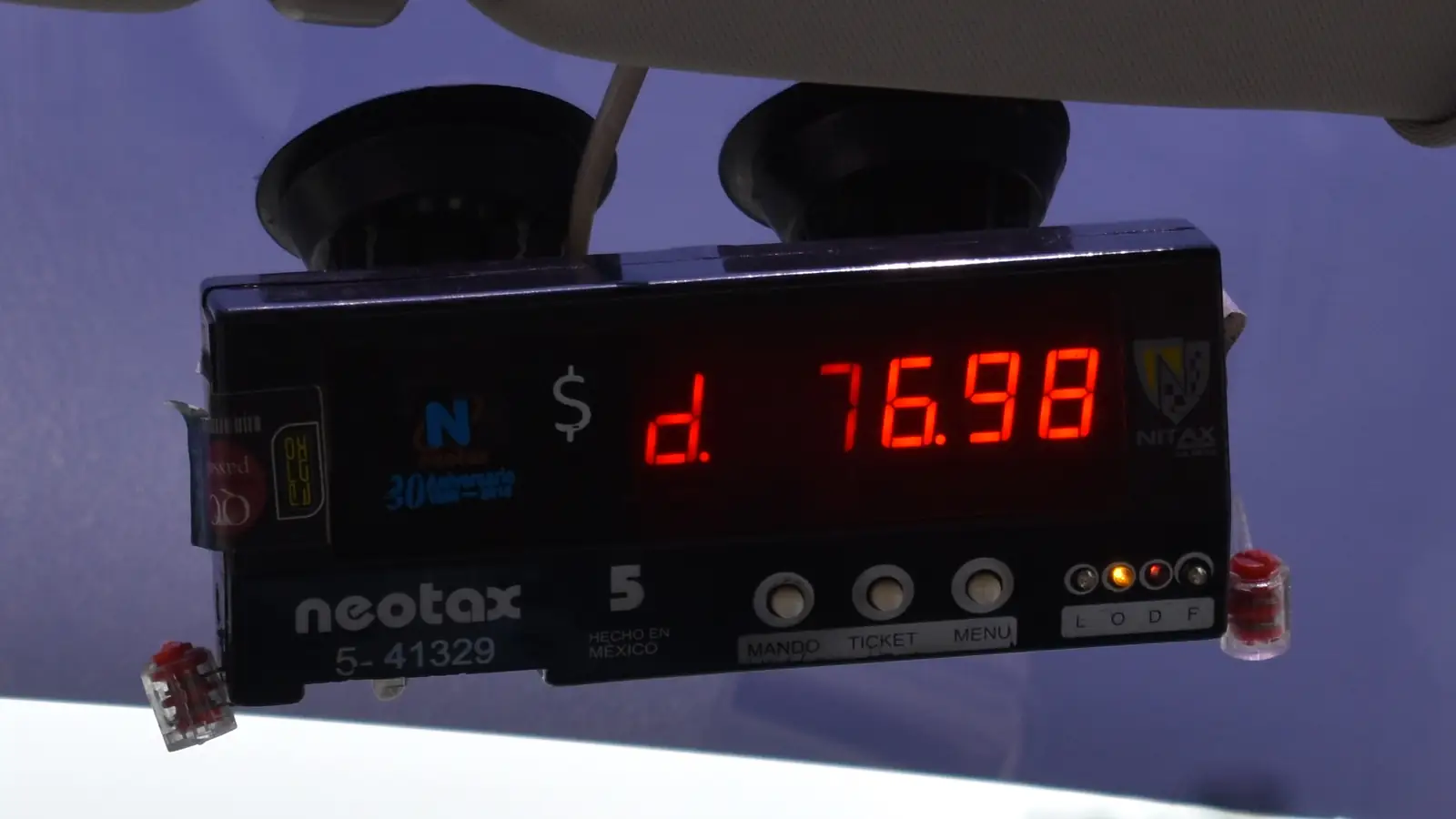 A taxi meter showing a fare in glowing red digits