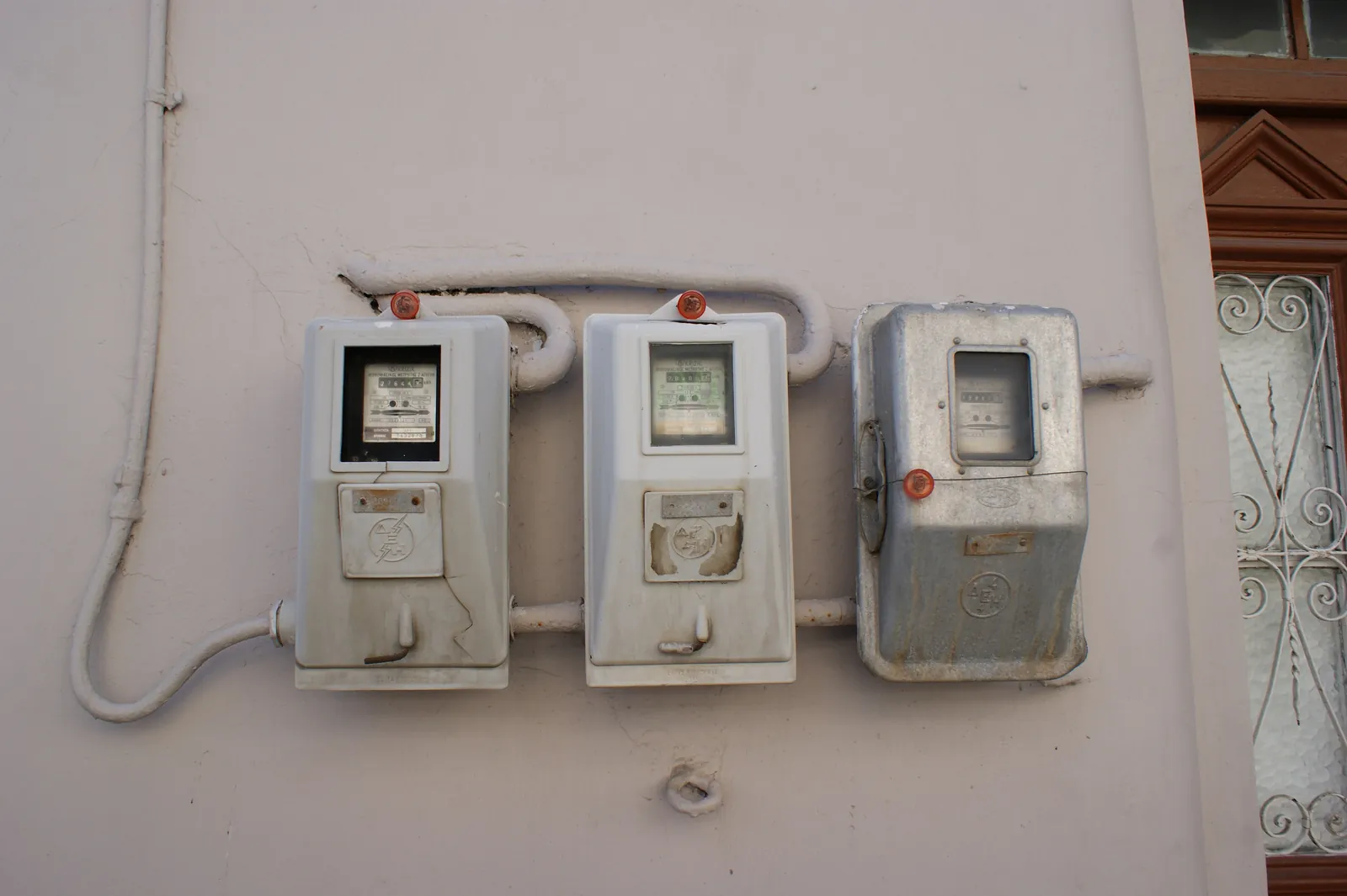 Three old electricity meters mounted on an outside wall