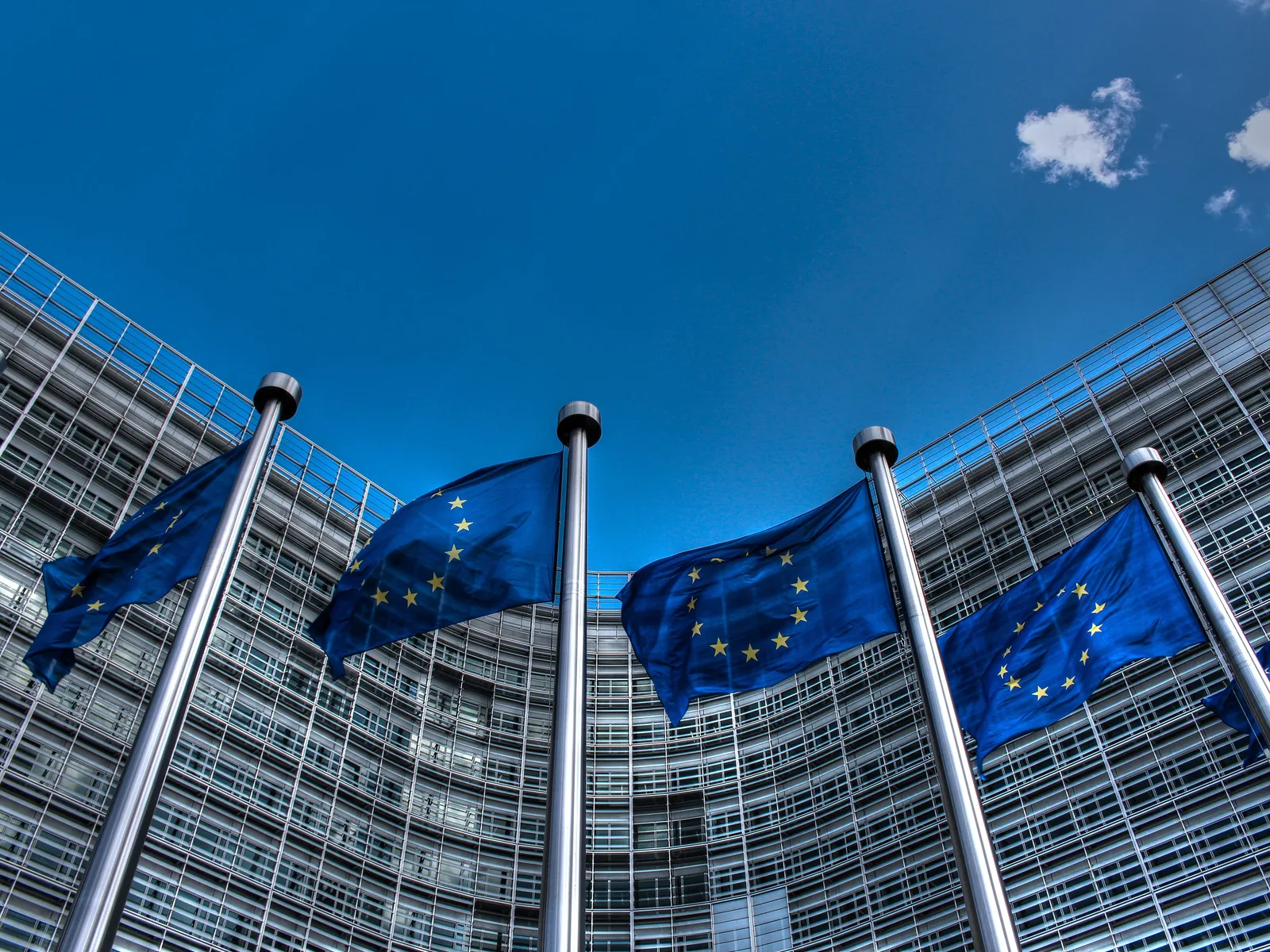 Four EU flags flying in front of the glass Berlaymont building in Brussels