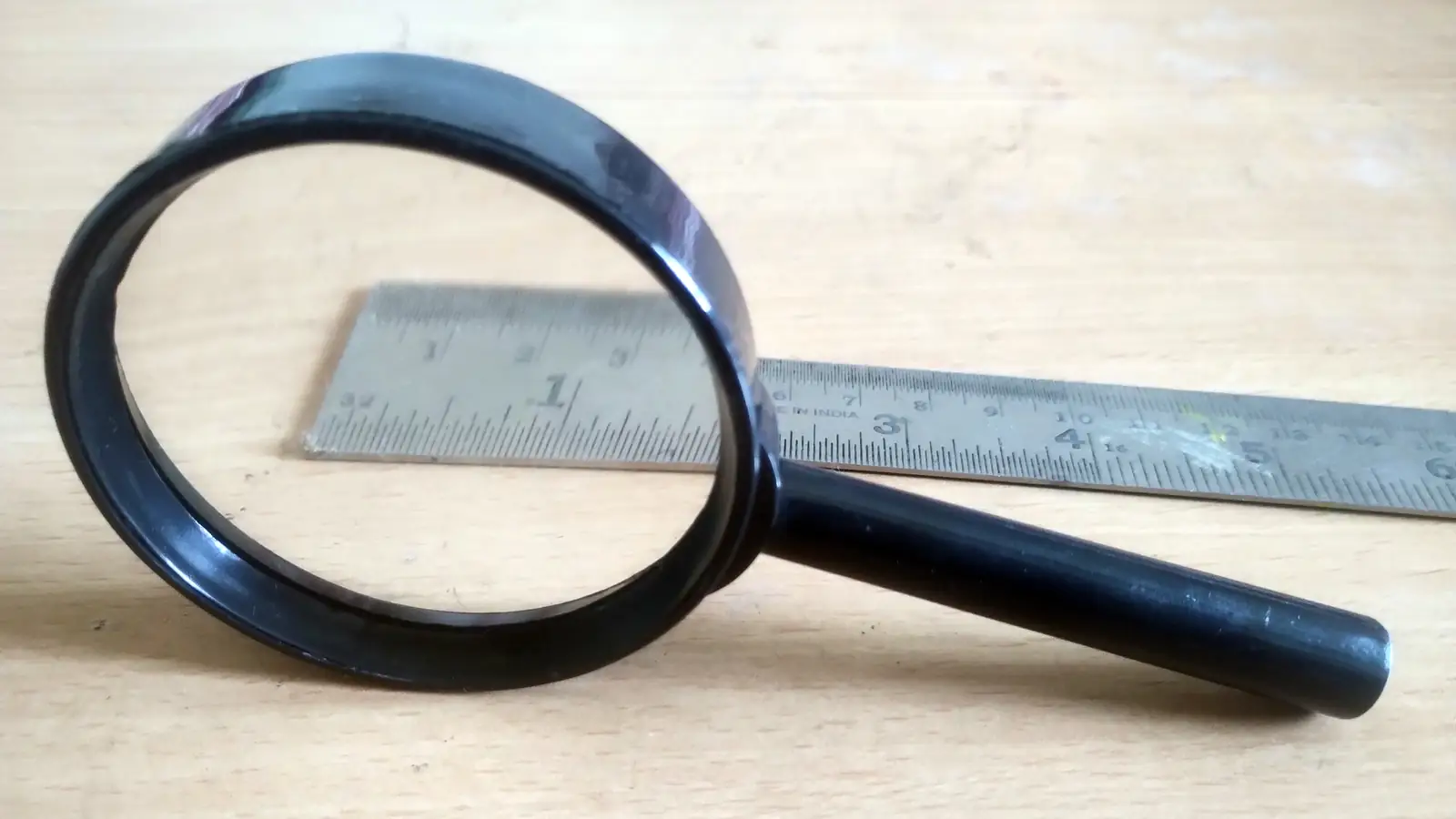 A magnifying glass resting on a metal ruler