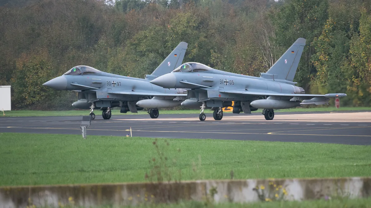 Two grey Eurofighter jets side by side on an airfield taxiway, parked for a pre-flight check