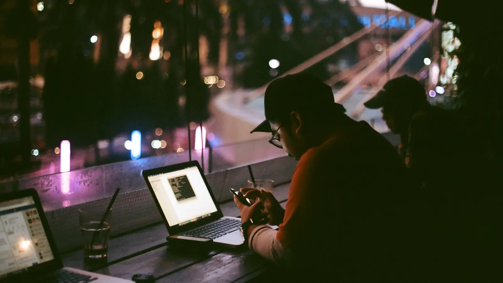 A person working on a laptop late at night in a dim room