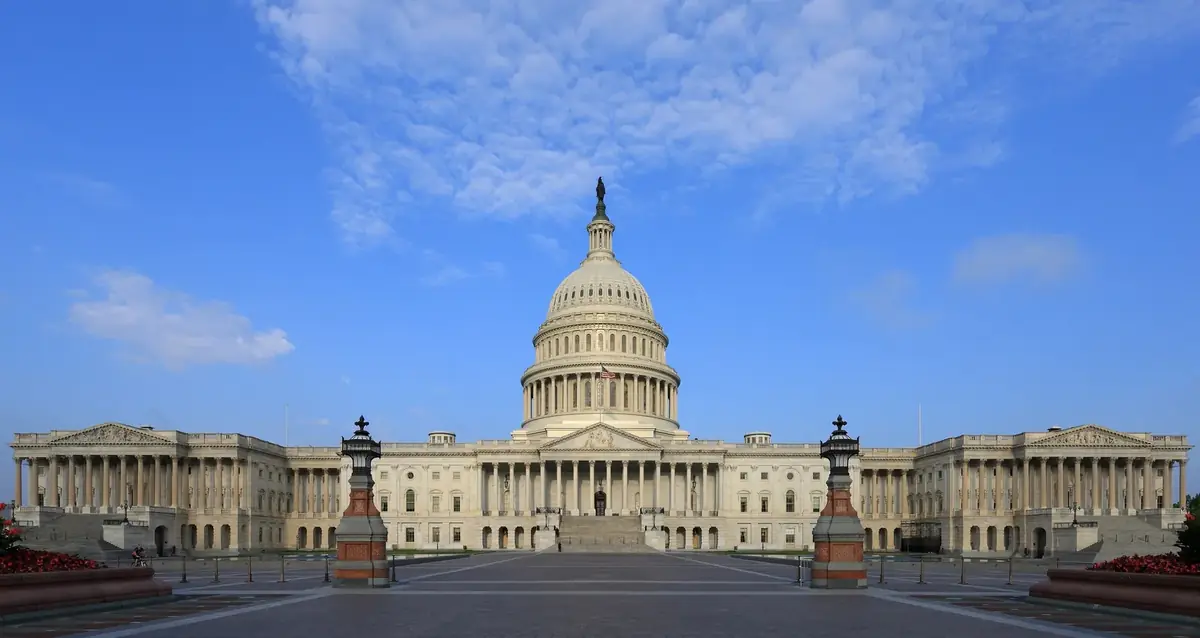 The US Capitol building under a blue sky with scattered clouds