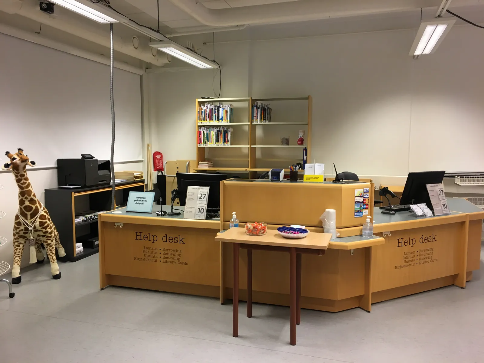 An empty library help desk with two computers and a toy giraffe